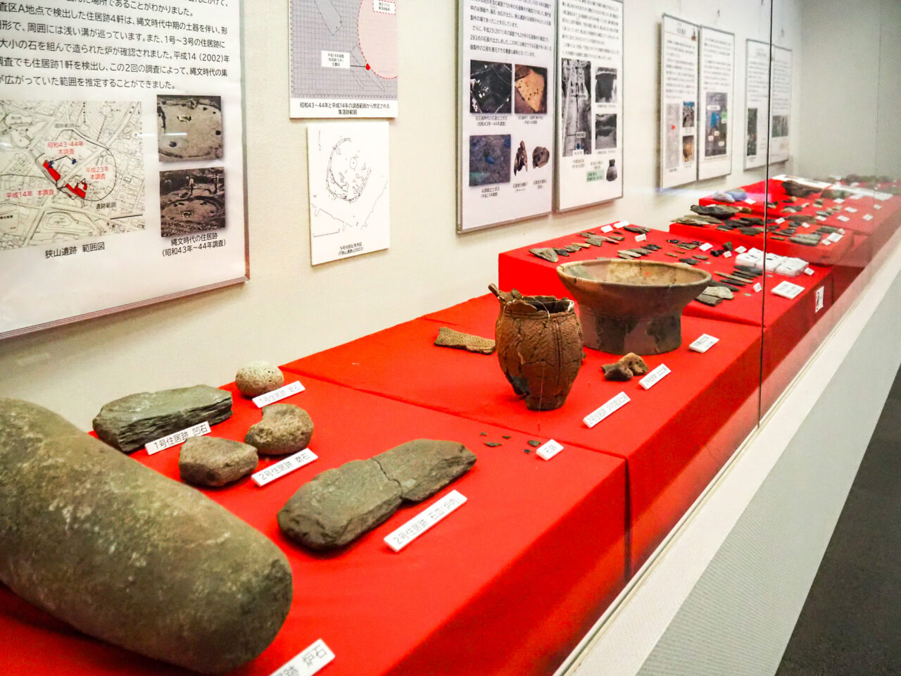 瑞穂町の遺跡から出土した土器や石器が並ぶ展示ケースとパネル解説