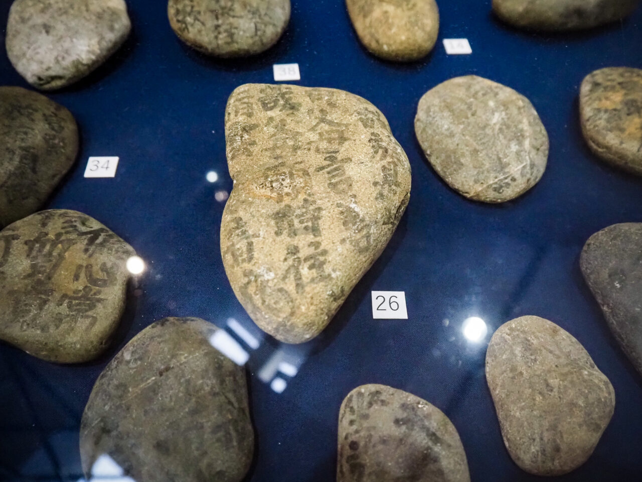 墨や彫りで文字が刻まれた小石（経石）の拡大展示
