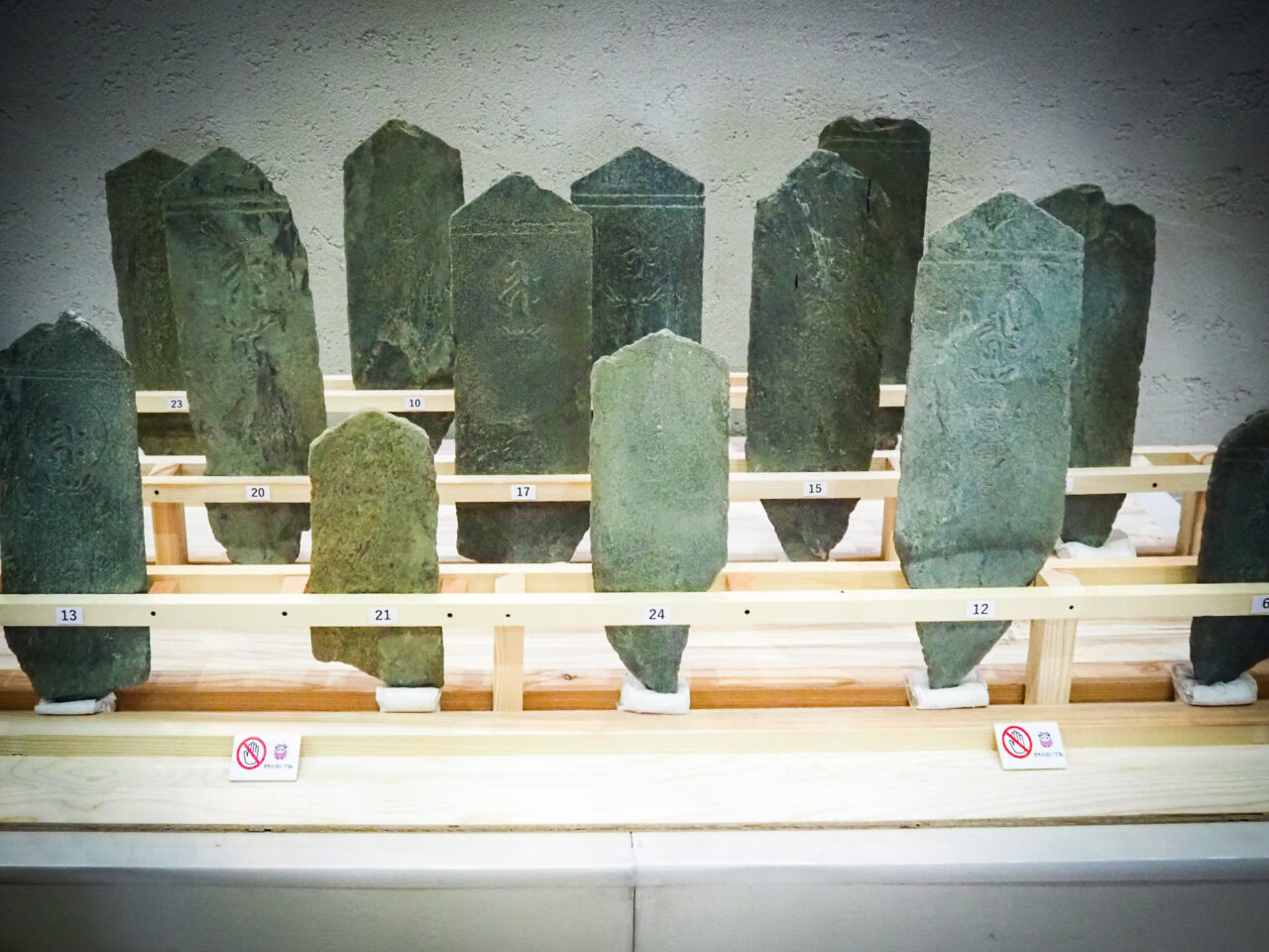 木枠に立てかけられて並ぶ緑泥片岩の板碑（中世の石造物）群