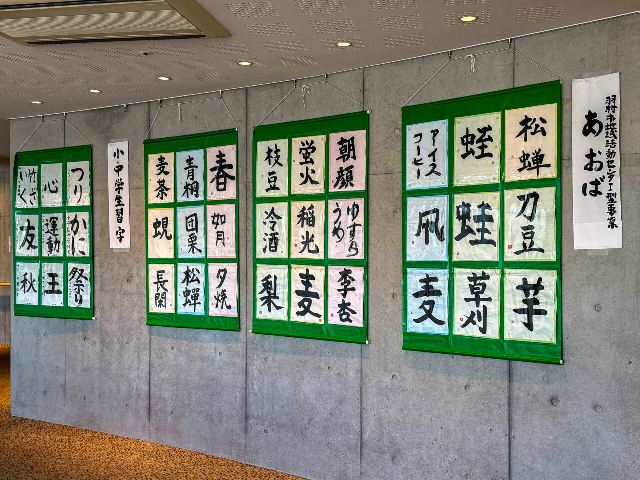 小中学生の学習字や地域団体の書道作品が展示された緑の掛け軸